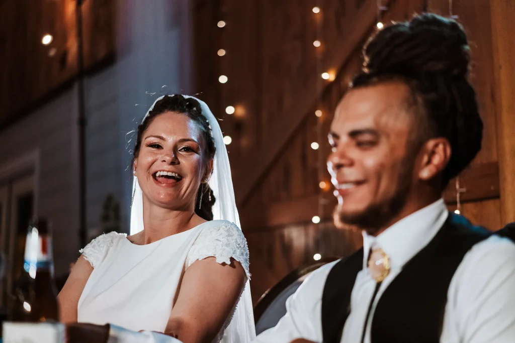The bride laughs joyfully beside the groom during their wedding reception at Masters Stables.