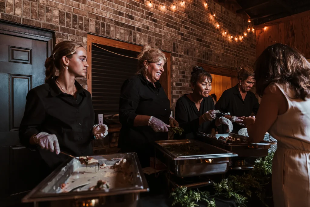 Catering staff serving dinner to guests during a wedding reception inside the Masters Stables venue in Fellsmere, Florida.