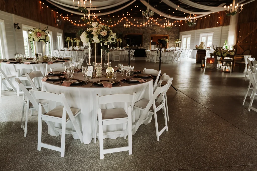 Elegant wedding reception tables with floral centerpieces and draped ceilings inside the banquet hall at Masters Stables in Fellsmere, Florida.